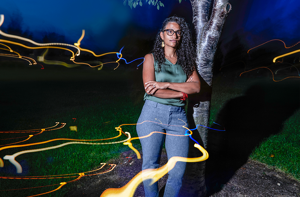 Eugenia South, MD, stands beside a tree in a park at night.